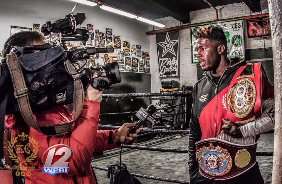 Boxer giving an interview holding multiple championship belts.