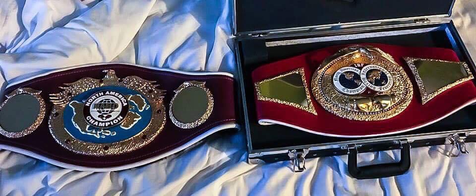 Two championship boxing belts displayed on a case.